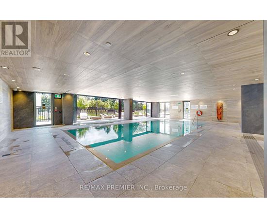 A large indoor swimming pool with a tiled floor and a ceiling with wooden panels.