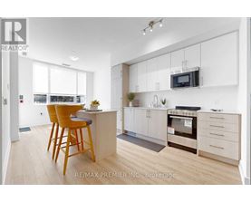 A kitchen with white cabinets and a wooden island with a bar stool.