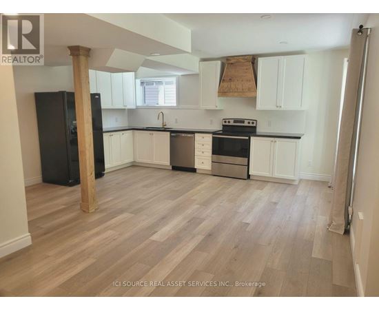 A kitchen with white cabinets and a black fridge.