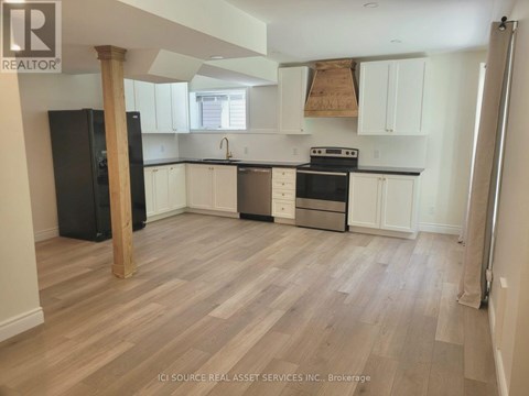 A kitchen with white cabinets and a black fridge.