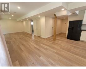 A spacious room with wooden flooring and white walls.
