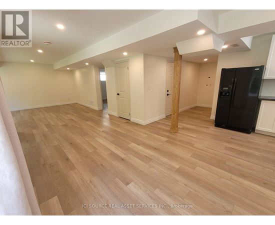 A spacious room with wooden flooring and white walls.