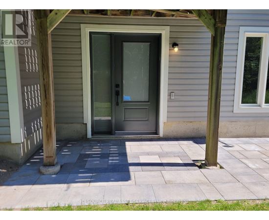 A grey door is in the middle of a concrete walkway.