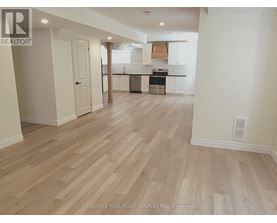 A spacious kitchen with white cabinets and a wooden floor.