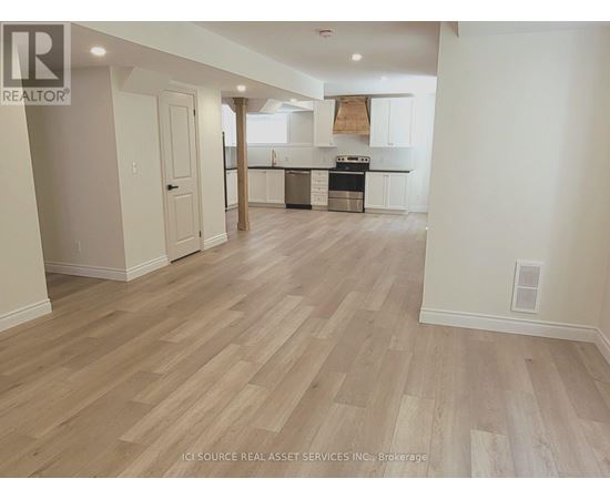 A spacious kitchen with white cabinets and a wooden floor.