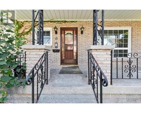 A house entrance with a brown door and black metal railings.