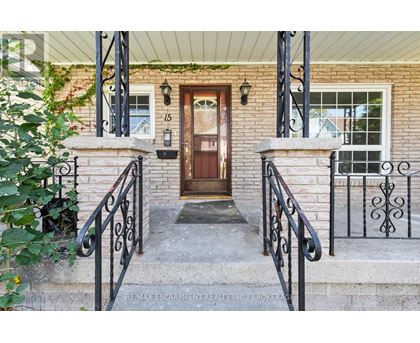 A house entrance with a brown door and black metal railings.