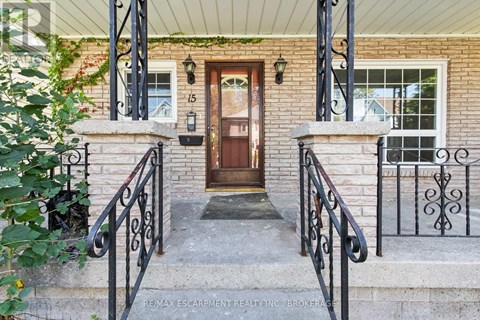 A house entrance with a brown door and black metal railings.