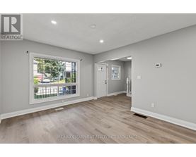 A spacious room with a large window and wooden flooring.
