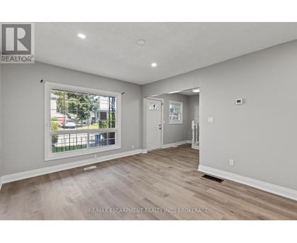A spacious room with a large window and wooden flooring.