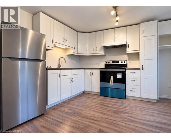 A kitchen with white cabinets and a stainless steel refrigerator.