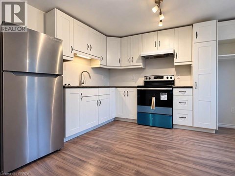 A kitchen with white cabinets and a stainless steel refrigerator.