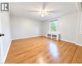 A room with wooden flooring and a window with a view of trees.