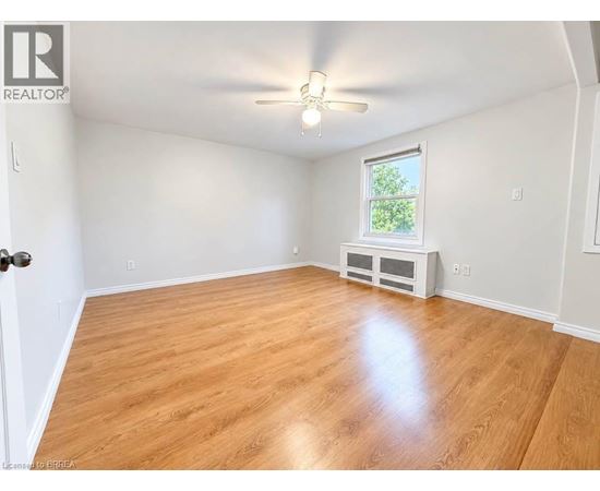 A room with wooden flooring and a window with a view of trees.