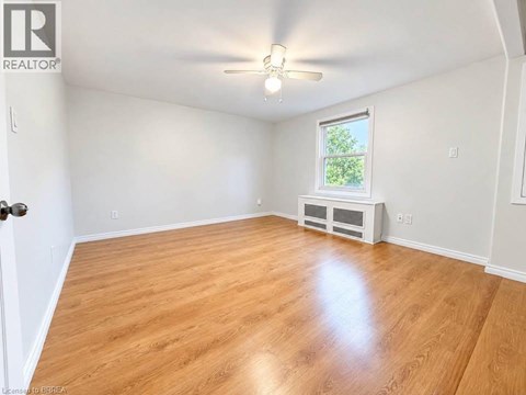 A room with wooden flooring and a window with a view of trees.