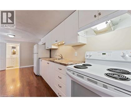 A white stove is in a kitchen with white cabinets and a white fridge.