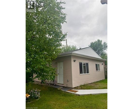 A small house with a porch and a tree in front.