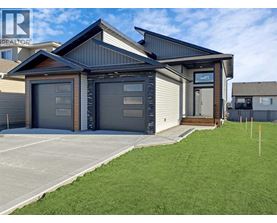 A modern house with a grey garage door is for sale.