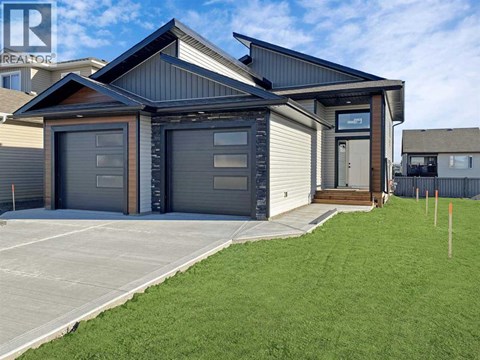 A modern house with a grey garage door is for sale.