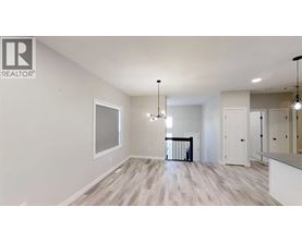 A spacious room with a large window, hardwood floors, and a chandelier.