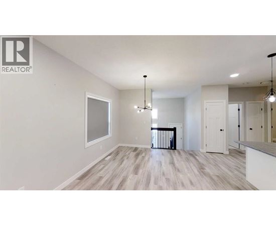 A spacious room with a large window, hardwood floors, and a chandelier.