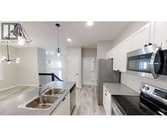 A modern kitchen with a stainless steel refrigerator and oven.