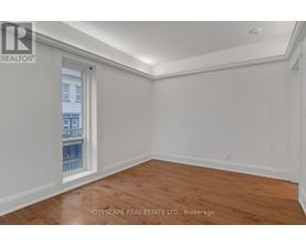 A room with wooden flooring and white walls, with a window showing a view of a building.