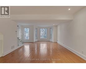A spacious room with wooden flooring and white walls.