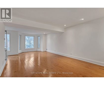 A spacious room with wooden flooring and white walls.