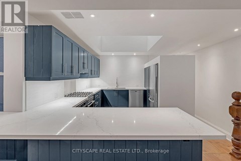 A modern kitchen with dark blue cabinets and a white marble countertop.