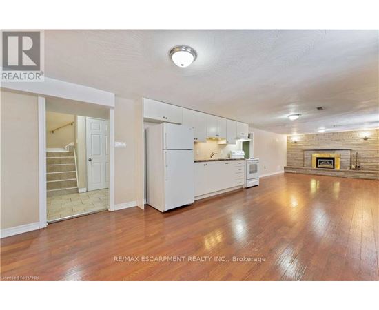 A spacious living room with wood flooring and a fireplace.