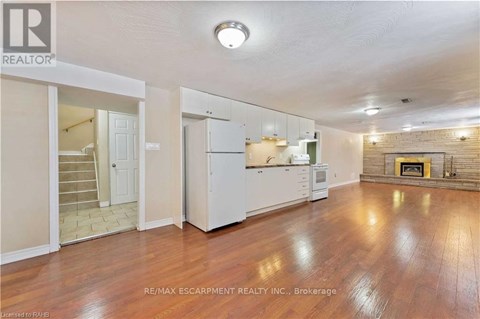 A spacious living room with wood flooring and a fireplace.