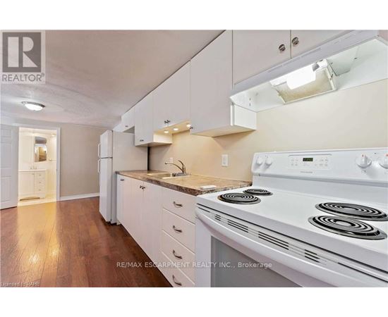 A white stove is in a kitchen with white cabinets and a white range hood.