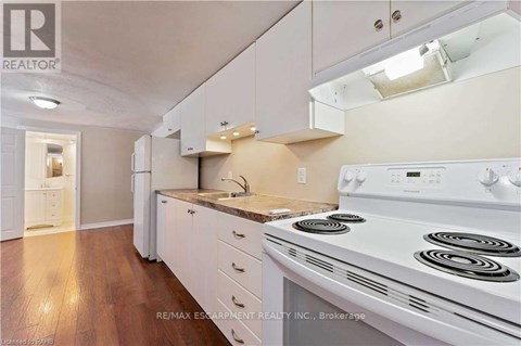 A white stove is in a kitchen with white cabinets and a white range hood.