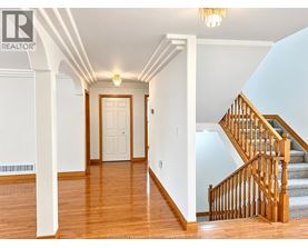 A hallway with a staircase and a chandelier.
