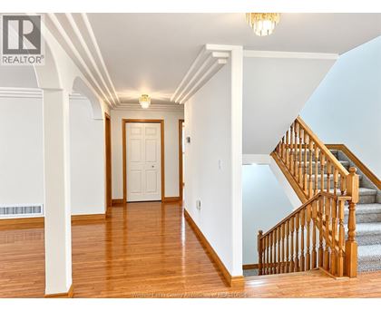A hallway with a staircase and a chandelier.