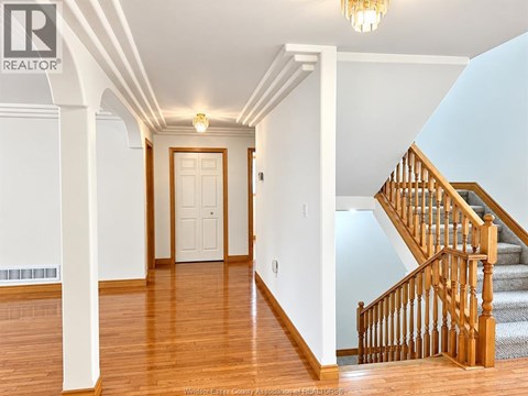 A hallway with a staircase and a chandelier.