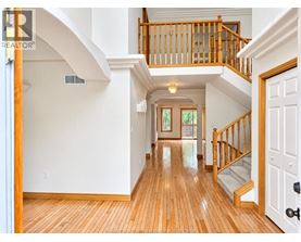 A large open space with a wooden floor and a staircase with a wooden railing.