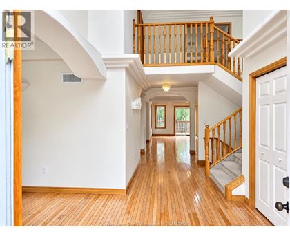 A large open space with a wooden floor and a staircase with a wooden railing.