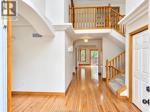 A large open space with a wooden floor and a staircase with a wooden railing.