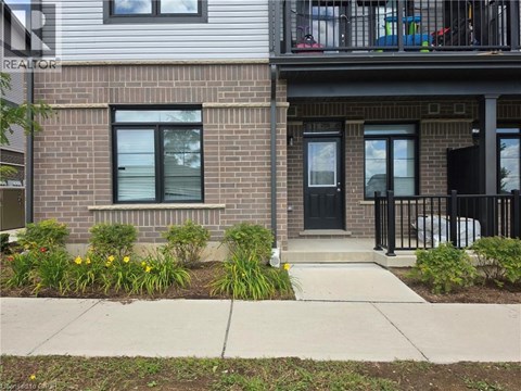A house with a black door and windows with a small garden in front.