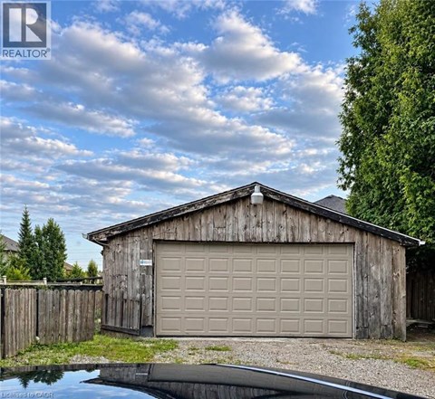 A wooden garage with a closed brown door is situated next to a pond.