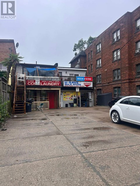 A white car is parked in front of a building with a sign that says "Clean Laundry.".