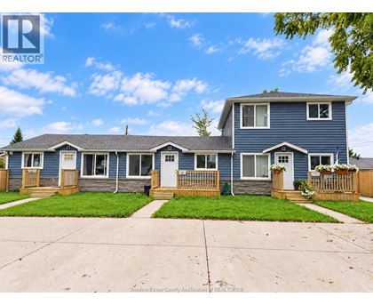 A blue house with a white door and windows is for sale.