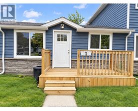 A blue house with a white door and a wooden deck.