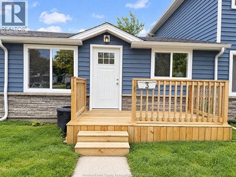 A blue house with a white door and a wooden deck.