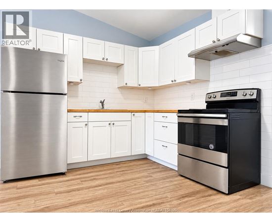 A kitchen with a stainless steel refrigerator and a black oven.