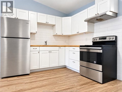 A kitchen with a stainless steel refrigerator and a black oven.