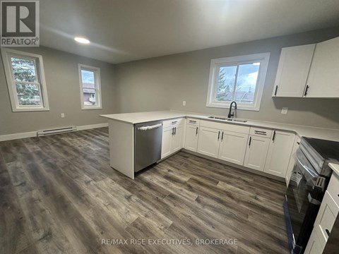 A kitchen with white cabinets and a wooden floor.