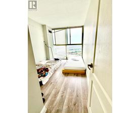 A bedroom with a bed and a window with blinds.